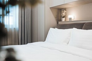 Een hotelkamer met een bed, gordijnen, een nachtkastje met een lamp en een potplant.