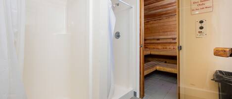 A dry sauna with a sign instructing not to add water, a shower area, and a wooden door.