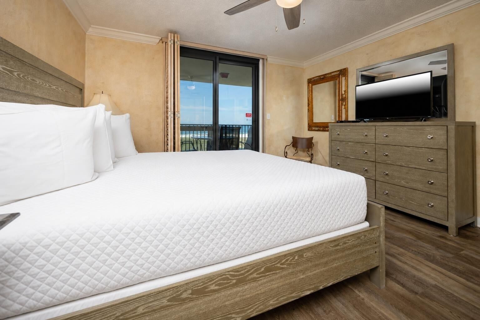 Een hotelkamer met een groot bed, een dressoir, een televisie en een balkon met uitzicht.