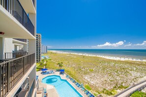 A hotel with a pool, beach view, and multiple balconies.