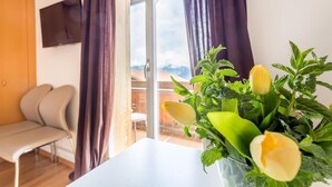 A room with a white table, a bench, and a window with curtains. - Hotel Sterne - Standard Apartment with Lake view (Beatenberg)