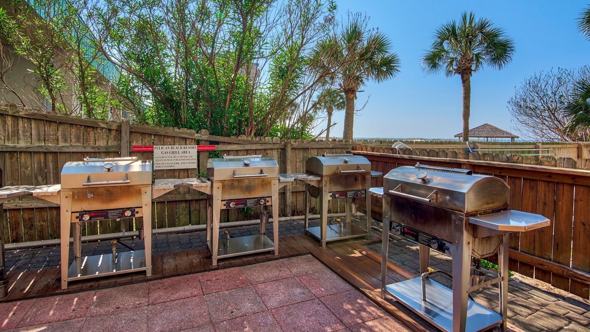 Ein Grillbereich mit Gasgrills am Pelican Beach Resort, umgeben von einer Holzlattenverkleidung.