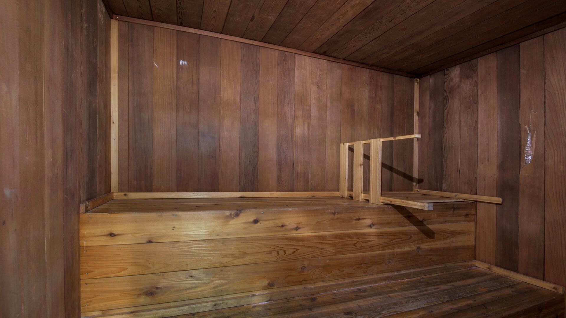 Un interior de madera con suelo, paredes, escalera y techo de madera.
