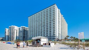 Um hotel alto com várias varandas e localização à beira-mar.