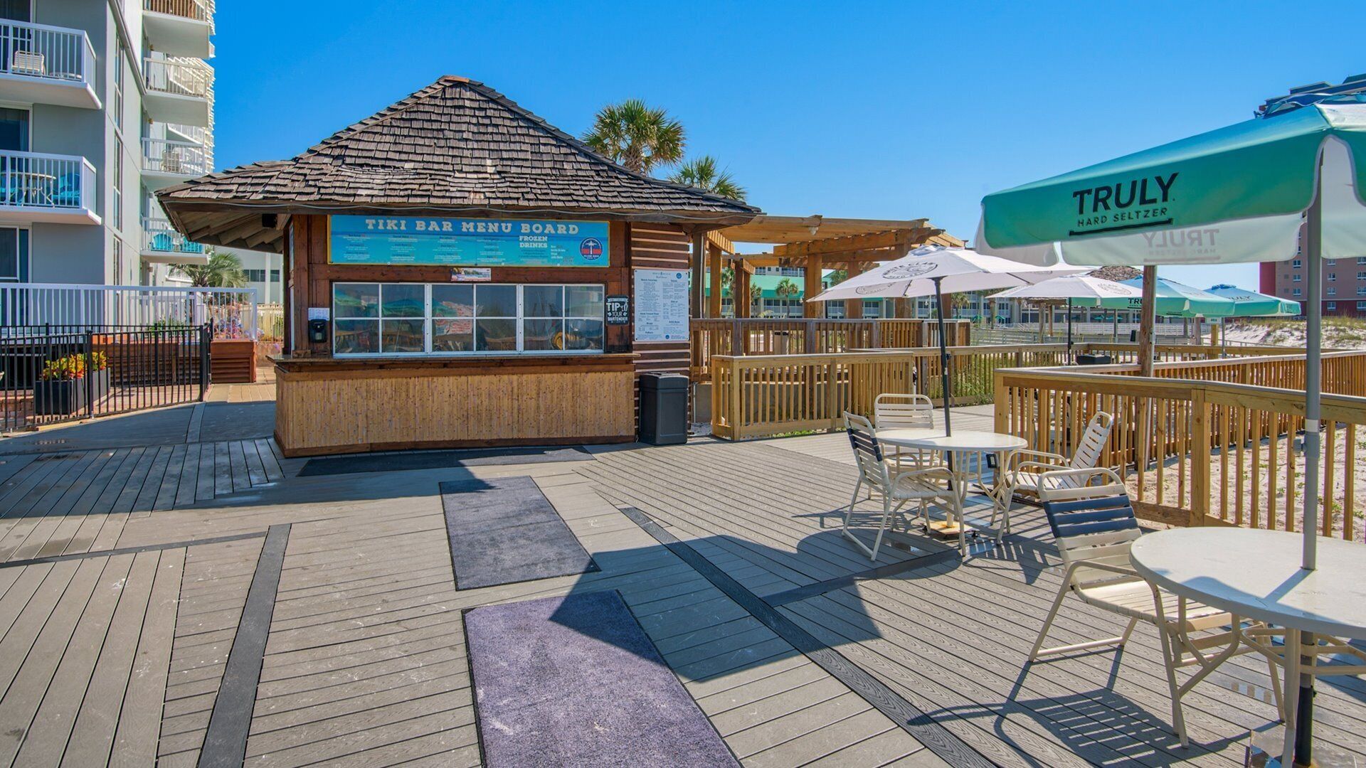 Eine Tiki-Bar mit Speisekarte, Außenbereich und einem TRULY Hard Seltzer Sonnenschirm.