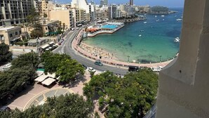 Un paysage urbain côtier avec des bâtiments, une plage et un port de plaisance.