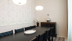 Une salle à manger avec une longue table, des chaises, un vase et un papier peint à motifs.