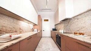 Cocina moderna con encimeras de mármol, electrodomésticos de acero inoxidable y armarios de madera.