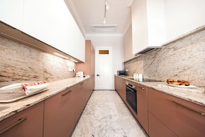 A modern kitchen with marble countertops, stainless steel appliances, and wooden cabinets.