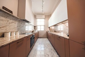 A modern kitchen with marble countertops, wooden cabinets, and a central island.