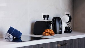 Un comptoir de cuisine avec un grille-pain, une machine à café et un croissant sur une assiette.