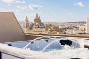 Una vasca idromassaggio con getti, vista su un paesaggio urbano con edifici a cupola e cielo sereno.