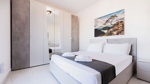 Une chambre moderne avec un grand lit, une armoire et un tableau représentant un paysage.