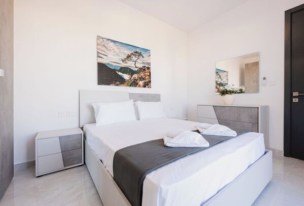 Una camera da letto moderna con un letto grande, un comodino, uno specchio e un quadro appeso al muro.