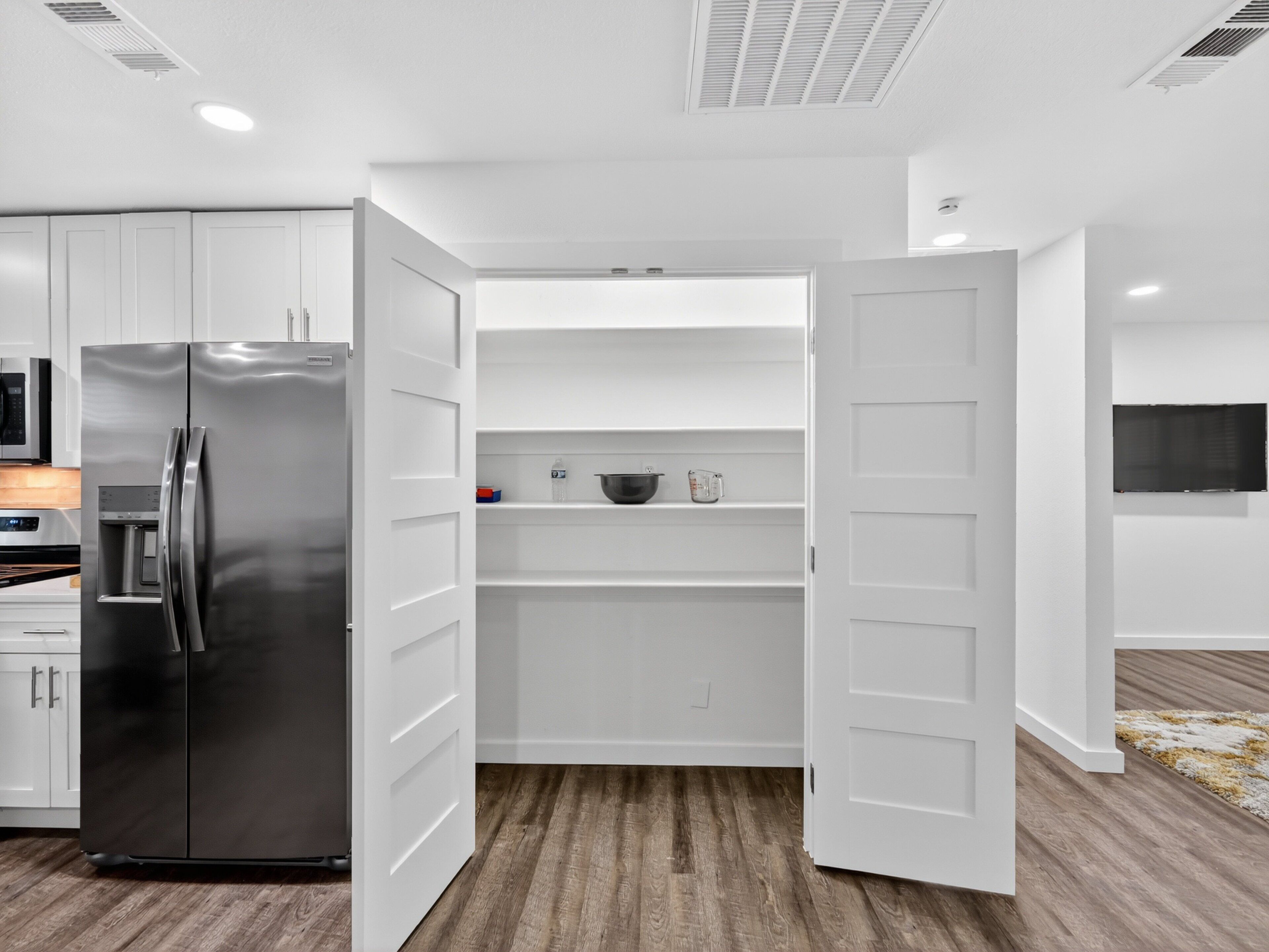 Una cocina moderna con armarios blancos, un refrigerador de acero inoxidable y un horno empotrado.