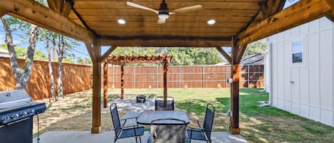 A covered patio with a grill, table, and chairs.