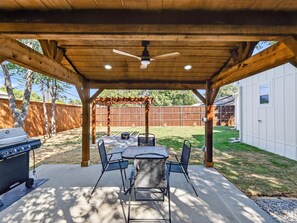 Un patio techado con una parrilla, una mesa y sillas.