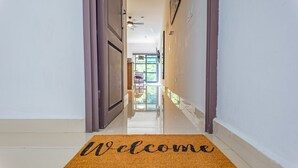 Un pasillo con un tapete de 'Welcome', una puerta y vista a una habitación con una mesa y sillas.