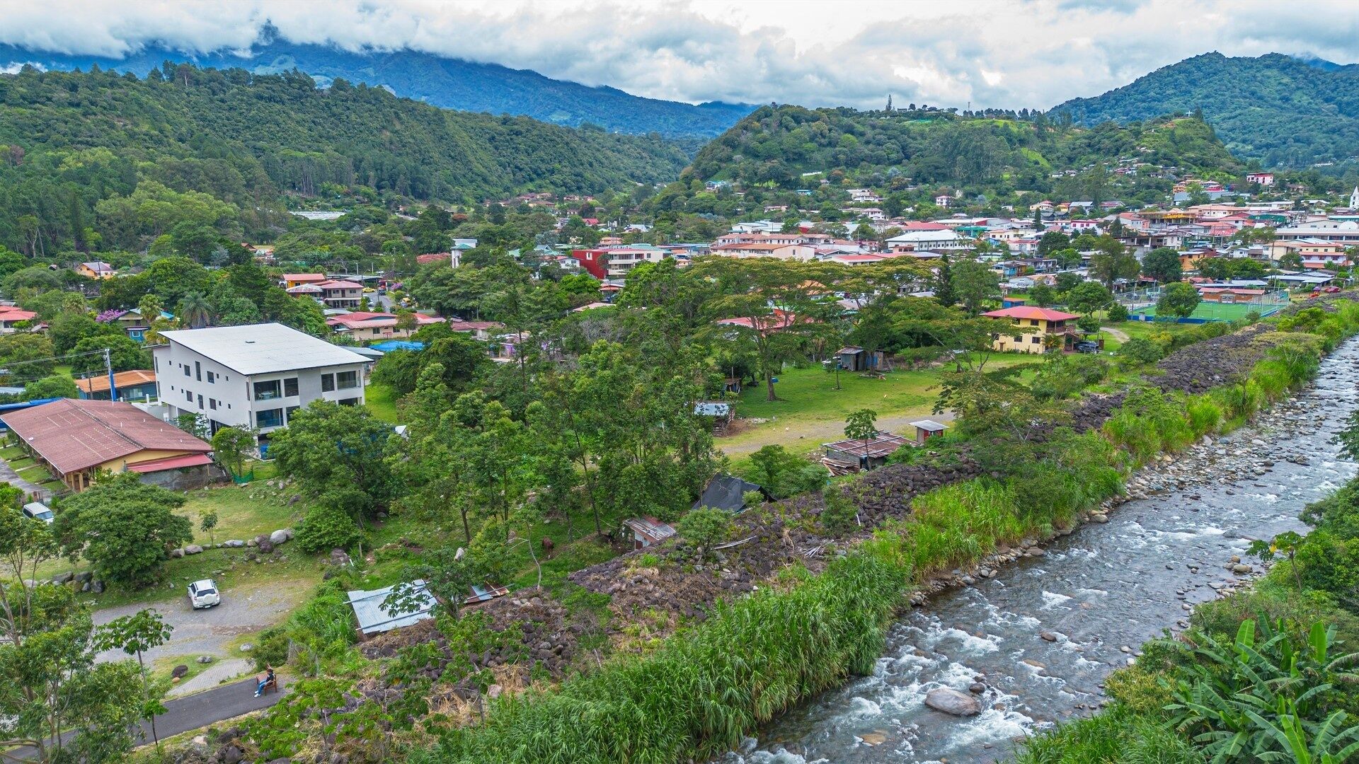 A town with a river, houses, and greenery.