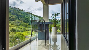Un balcón con una silla y una planta en maceta, con vista a un paisaje verde y exuberante.