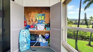 A room with a wooden door, a view of a golf course, and various sports equipment. - Kksr#6301 Ocean/Golf Course Views, Top Floor, Corner Unit, Cathedral Ceilings (Kailua Kona)
