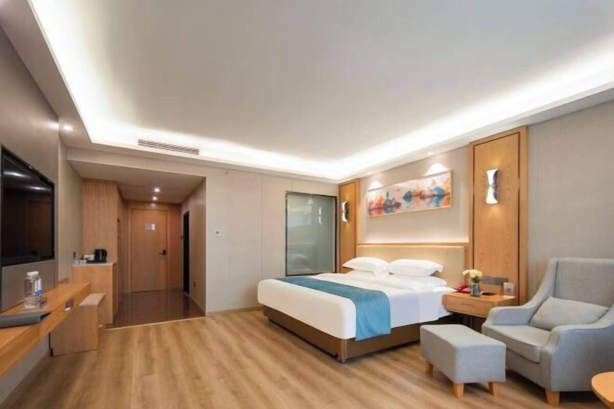 A modern hotel room with a large bed, a desk, a chair, and a TV.