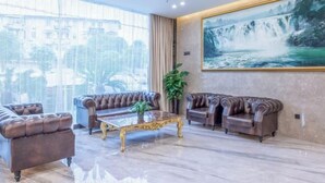 A spacious living room with leather sofas, a marble coffee table, and a large painting of a waterfall. - Garden Holiday Hotel (Guilin Liangjiang Sihu University of Technology) (Guilin)