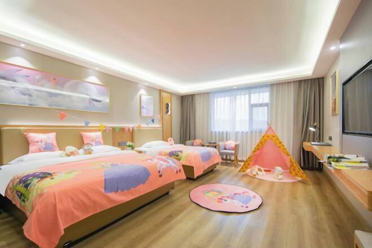 A hotel room with two beds, a play tent, and a round table.