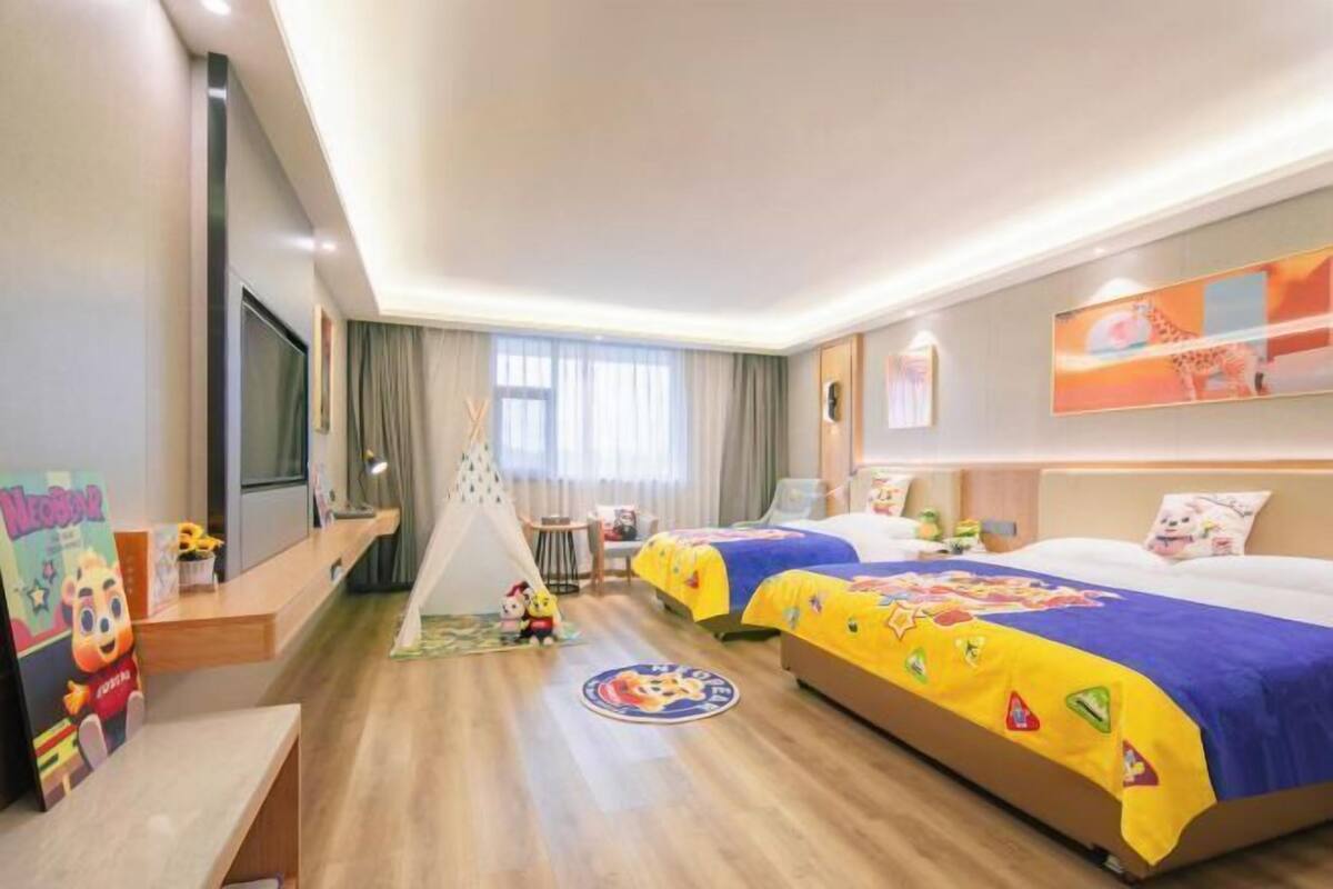 A hotel room with two beds, a desk, a chair, a TV, and a window with curtains.