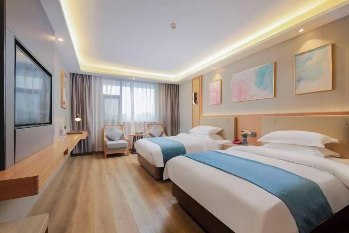 A hotel room with two beds, a desk, and a chair.