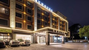 A multi-story hotel with a modern facade, illuminated signage, and a parking area with several cars. - Garden Holiday Hotel (Guilin Liangjiang Sihu University of Technology) (Guilin)