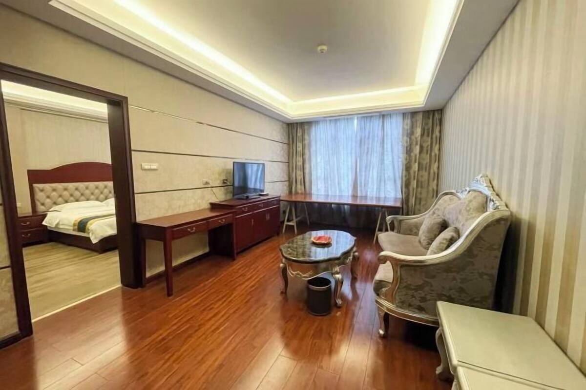 A hotel room with a bed, a desk, a TV, a sofa, and a small table.