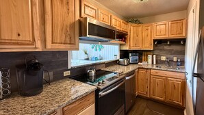 Eine Küche mit Holzschränken, Granit-Arbeitsplatten, Edelstahlgeräten und einer Spritzschutzwand.