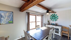 Ein Essbereich mit einem Holztisch, weißen Stühlen, einer Karte an der Wand und einem dekorativen Windrad.