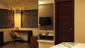 A hotel room with a bed, a desk with a chair, a television, and a wardrobe. - The Platinum Boutique Inn Hotel (Hyderabad)