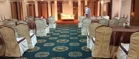 A conference room with rows of chairs, a carpeted floor, and a central stage.