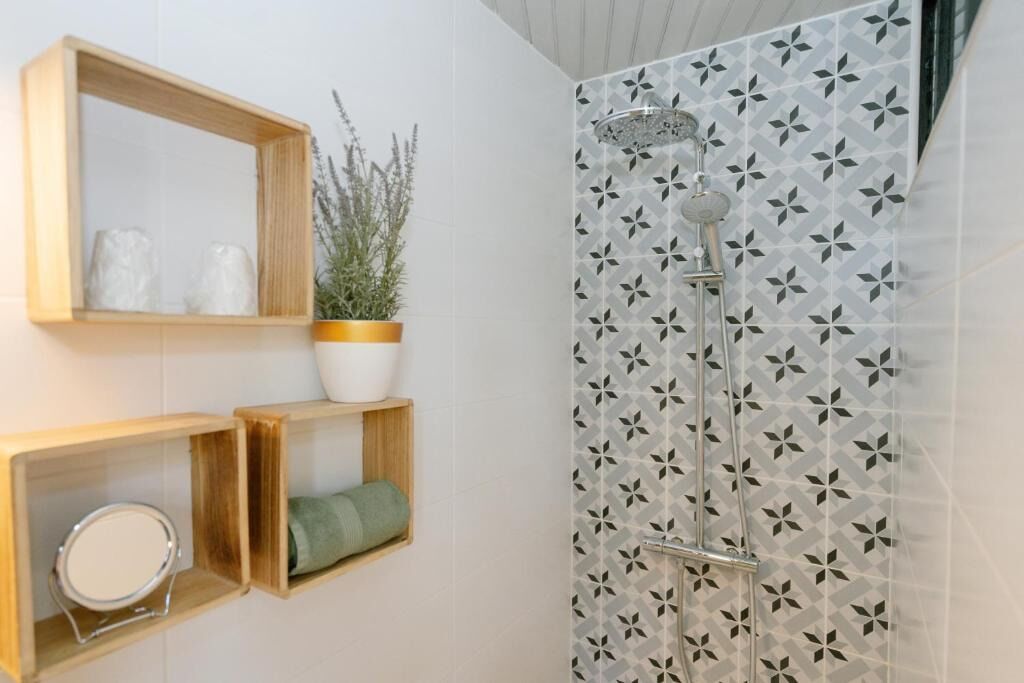 A bathroom with a shower, a mirror, and shelves with toiletries.