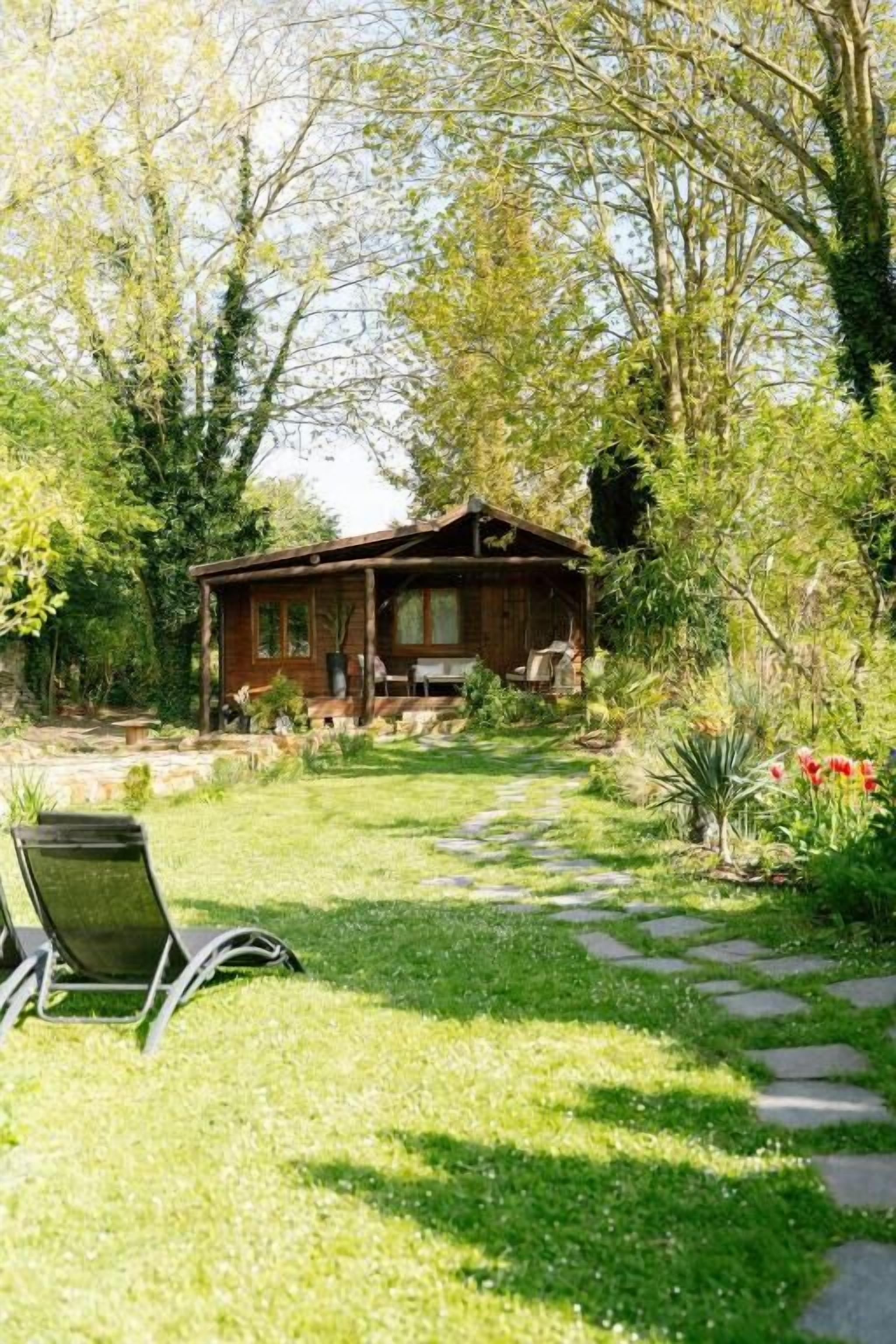 A rustic cabin with a stone pathway leading to a wooden deck.