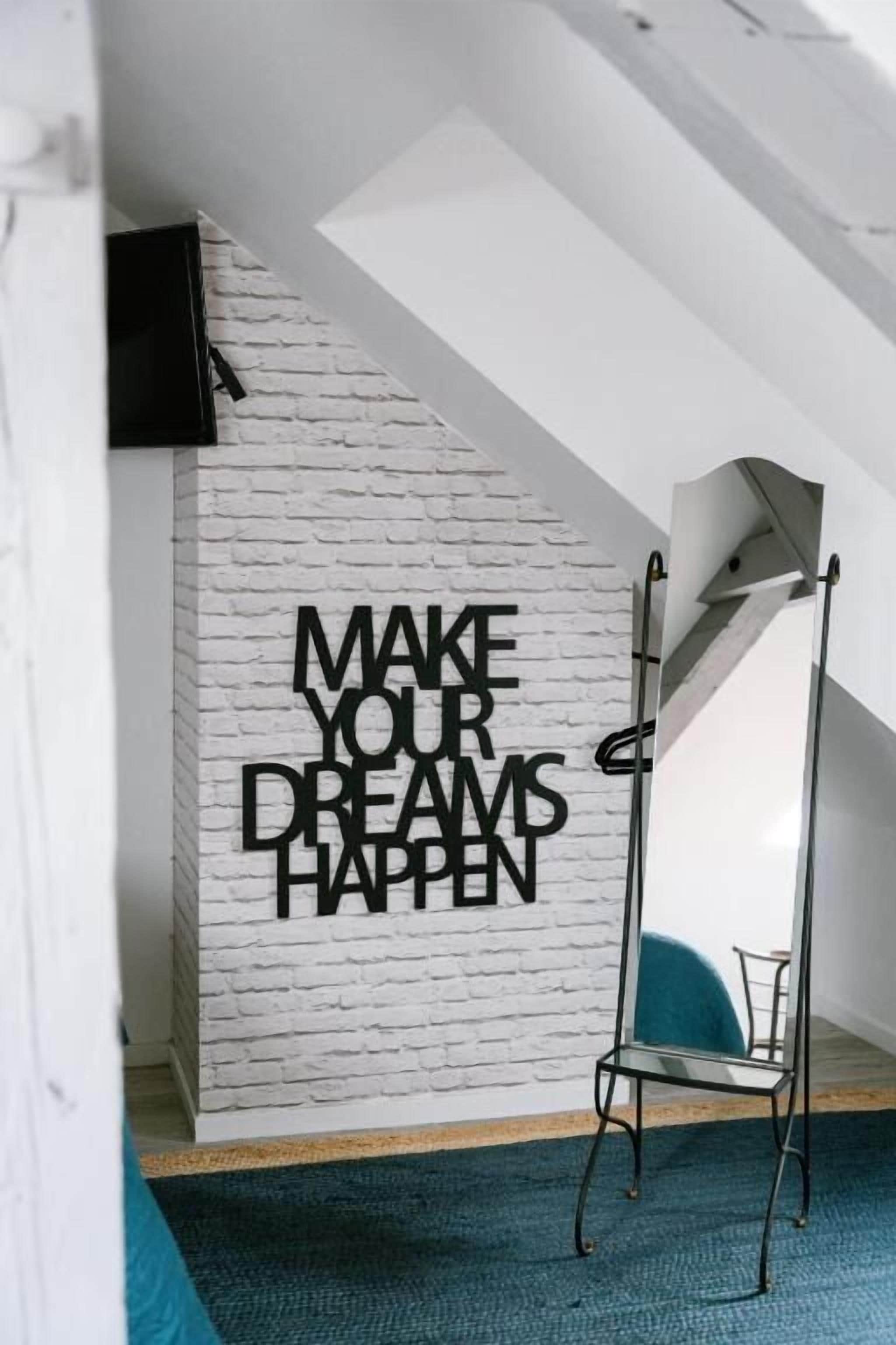 Une pièce avec un mur en briques blanches, une citation inspirante, un grand miroir et une moquette bleue.