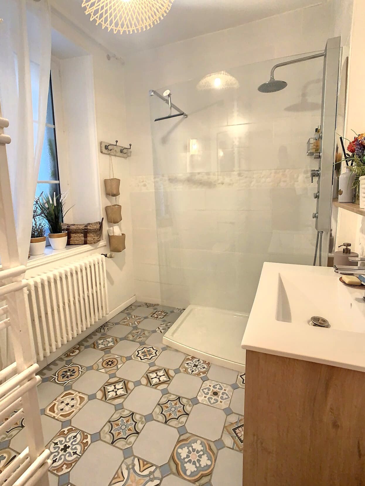 A modern bathroom with a shower, a white sink, and a patterned floor.