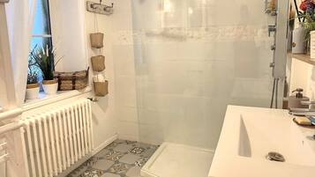 A modern bathroom with a shower, a white sink, and a patterned floor.