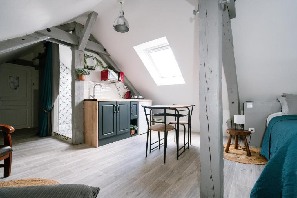A loft-style room with a kitchen area, a dining table, and a bed.