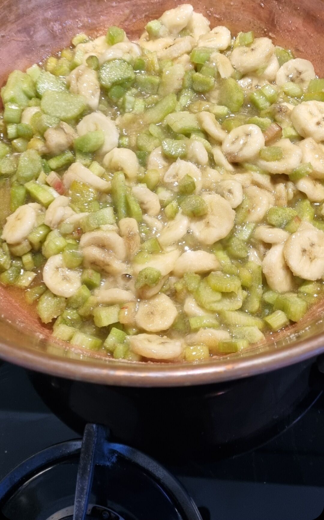 A cooking pan with sliced bananas and green vegetables.