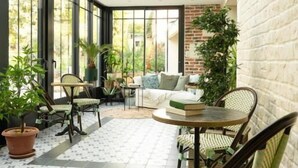 A sunlit room with a glass ceiling, a brick wall, and a patterned floor. - Les Glycines de Monchy (Monchy-Humieres)