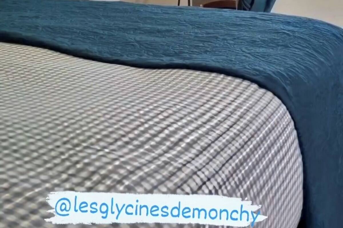 Une chambre avec un lit, un mur orné d’un texte motivant, une fenêtre avec des rideaux et un porte-vêtements suspendu.