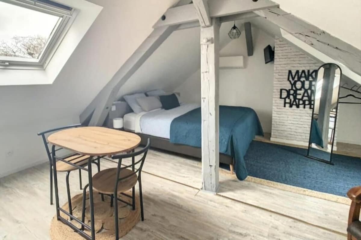 A small, attic-style bedroom with a bed, a table, and a chair.