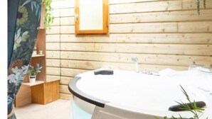 A spa room with a hot tub, wooden walls, a wooden ceiling, and a window. - Les Glycines de Monchy (Monchy-Humieres)