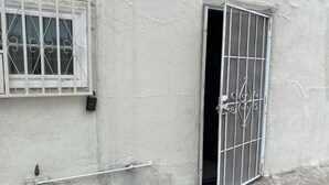 Ein weißes Gebäude mit vergittertem Fenster und einer Tür.