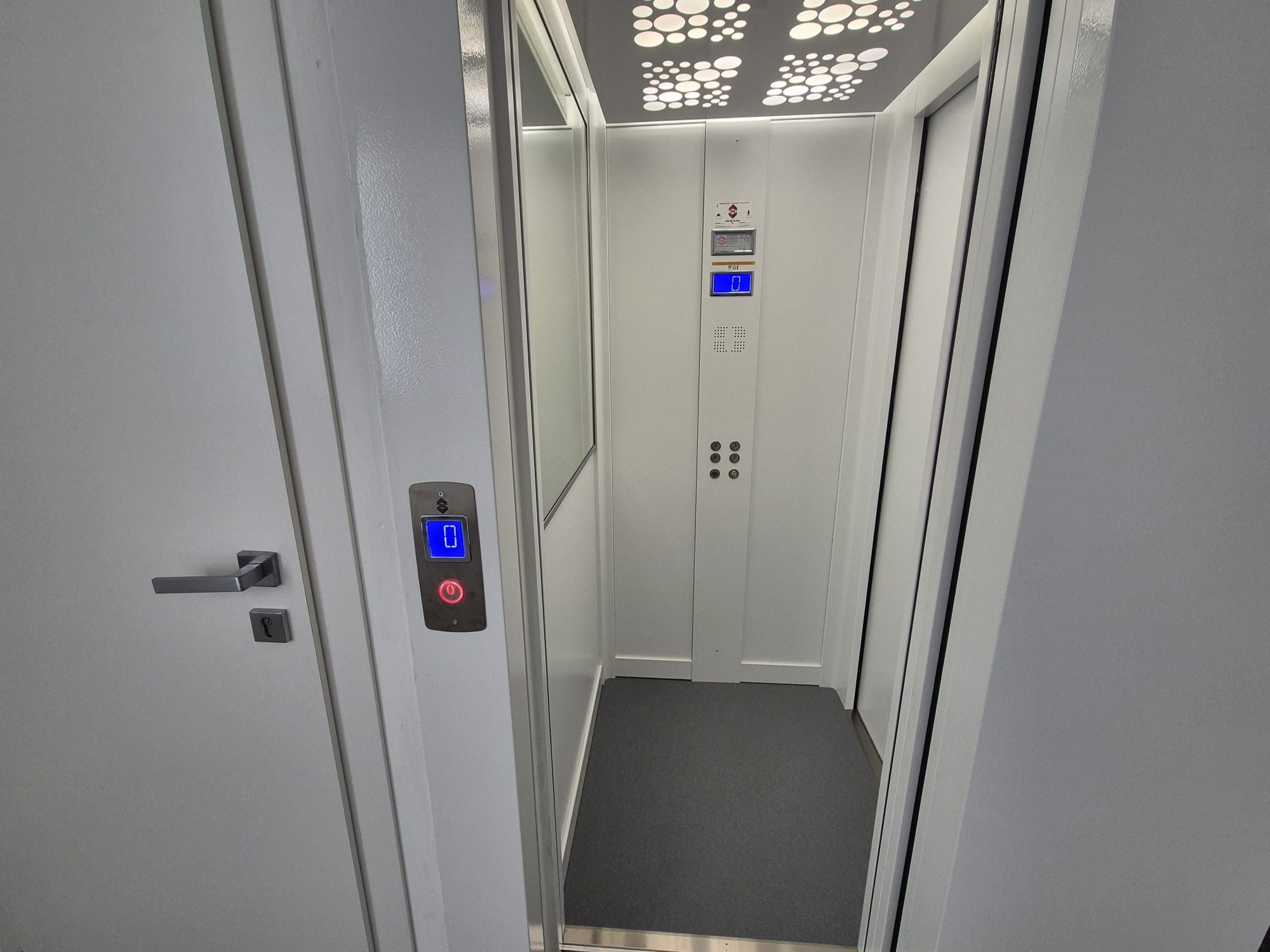 An elevator with a digital display, control panel, and emergency button.