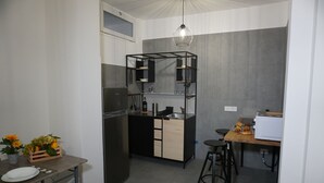 Une cuisine compacte dotée d’un réfrigérateur encastré, d’un plan de travail en bois et d’un luminaire suspendu.